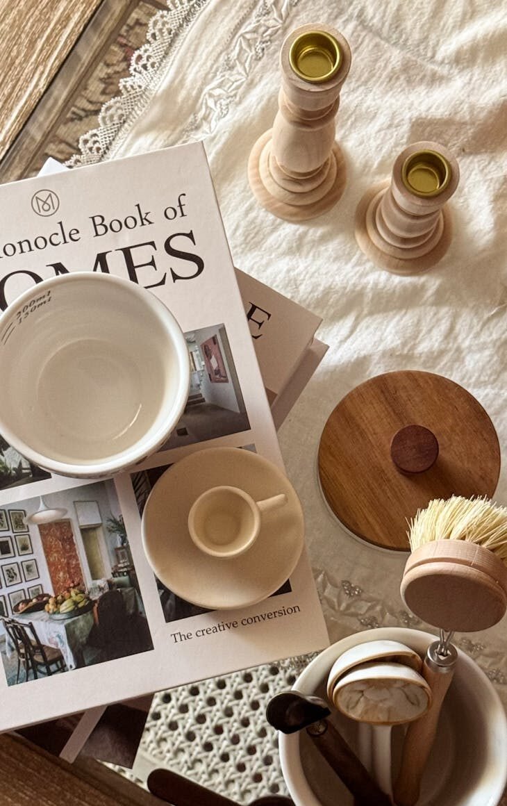 Minimalist kitchen setup with coffee cups, books, and wooden decor on a cozy table.